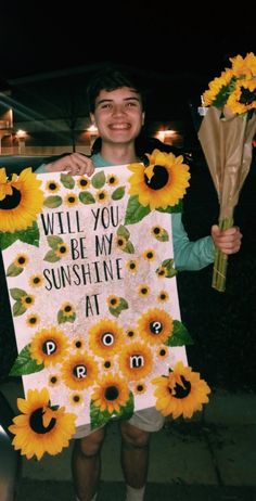 a man holding up a sign with sunflowers on it