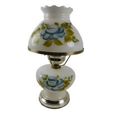 a white vase with blue flowers on it is sitting on a metal stand and has a gold base