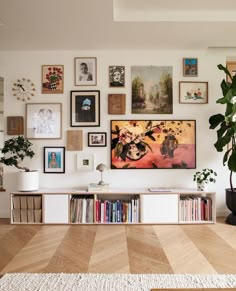 a living room filled with lots of pictures on the wall and plants in vases