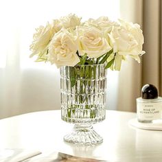 a glass vase filled with white flowers on top of a table