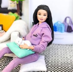 a doll sitting on a pillow holding a cat