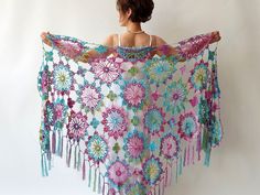 a woman is holding up a crocheted shawl