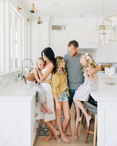 a group of people standing in a kitchen next to each other with their arms around one another