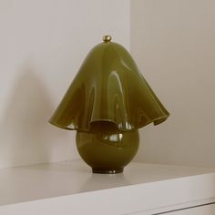 a green glass lamp sitting on top of a white shelf next to a wall mounted cabinet