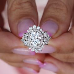 a woman's hand holding a diamond ring with pink nails and manicures