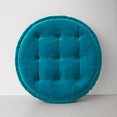 a blue round cushion sitting on top of a white floor