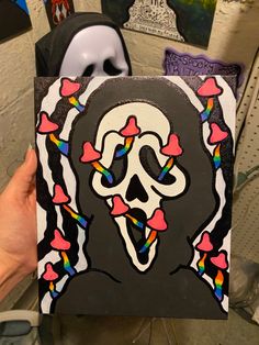 a person holding up a piece of art that looks like a skull with hearts on it