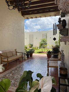 an open patio area with potted plants and chairs on the floor, in front of a white building