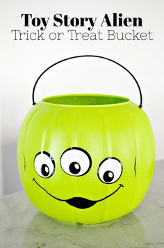 a green pumpkin shaped trick or treat bucket sitting on top of a table with the words toy story alien