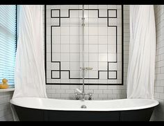 a black and white bath tub sitting in a bathroom next to a window with sheer curtains