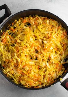 a pan filled with coleslaw and carrots on top of a stovetop