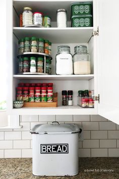 an organized pantry with white cabinets and lots of food in the bottom shelf, labeled bread