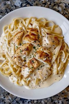 a white plate topped with pasta covered in sauce and chicken breast pieces on top of it