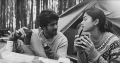 black and white photograph of two people sitting at a table in front of a tent