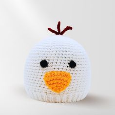 a crocheted white bird with orange beak and black eyes on it's head