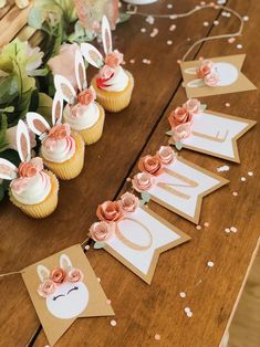 some cupcakes are sitting on a table with bunnies and flowers around them