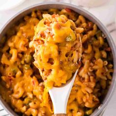 a ladle full of macaroni and cheese with a wooden spoon in it