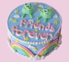 a heart shaped cake with the words friends forever written on it and two frogs sitting on top