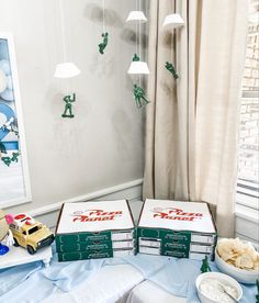 two pizza boxes sitting on top of a table next to a bowl of chips and a plate