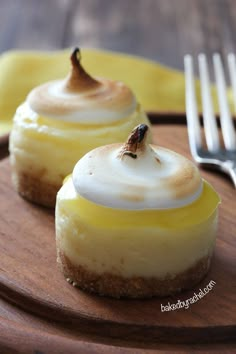 two desserts with icing on them sitting on a wooden table next to a fork