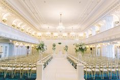 an indoor wedding venue with rows of chairs and chandeliers on either side of the aisle