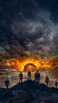 a group of people standing on top of a hill under a dark sky with clouds