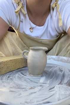 a woman is making a vase out of clay