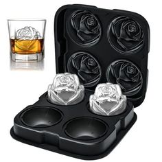 an ice cube tray with four roses in it and two glasses on the other side