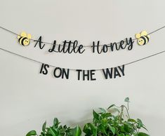 a little honey is on the way banner hanging from a string with bees and leaves