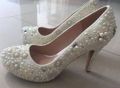 a pair of white high heels with pearls on them