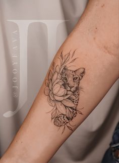 a woman's arm with a tattoo on it that has a leopard and flowers on it