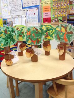 some paper trees are sitting on top of a wooden table in front of a bulletin board