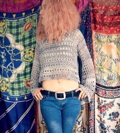 a woman is standing in front of some colorful fabrics with her hands on her hips