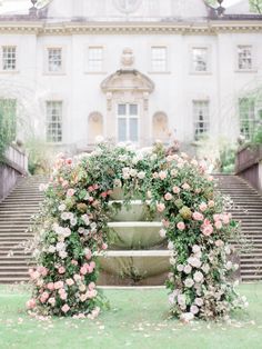 an outdoor wedding ceremony with flowers and greenery on the steps to a large building