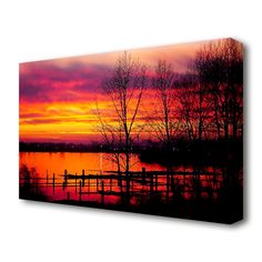 a colorful sunset over a lake with trees in the foreground and a dock on the other side