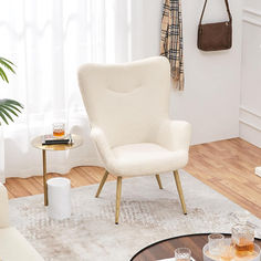 a living room with white furniture and wood flooring, including a chair in the center