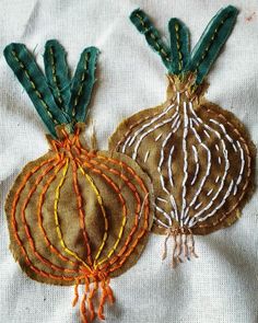 two hand embroidered ornaments on a white cloth