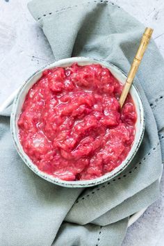 a bowl filled with red sauce sitting on top of a blue napkin next to a wooden spoon