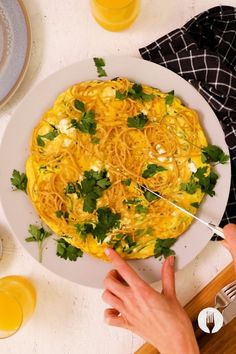 a plate of spaghetti with parsley on top and someone holding a fork over it