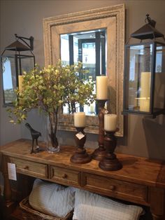 a wooden table topped with candles next to a mirror