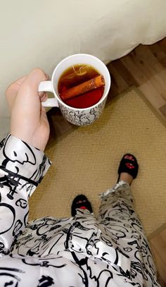 a person holding a cup of tea and some carrots