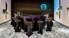 a room with several stools and a bar in the middle that has a circular table on it