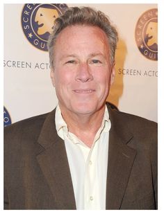 a man in a brown suit and white shirt smiles for the camera at an event