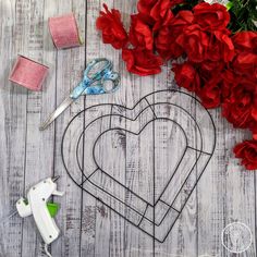 scissors, flowers and other crafting supplies are laid out on a wooden table next to a wire heart