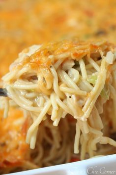 a spoon full of noodles and vegetables being lifted from a white casserole dish