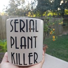 a hand holding a coffee mug with the words serial plant killer written on it in black