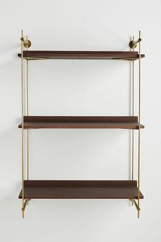 three shelves with brass handles and wooden shelves on each side, against a white wall