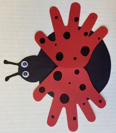 a lady bug made out of paper on top of a white surface with black dots