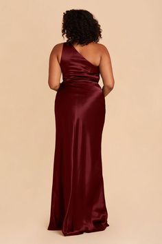 a woman in a long burgundy dress with one shoulder and an asymmetrical back