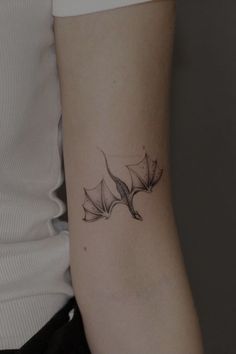 a black and white photo of a woman's arm with a leaf tattoo on it